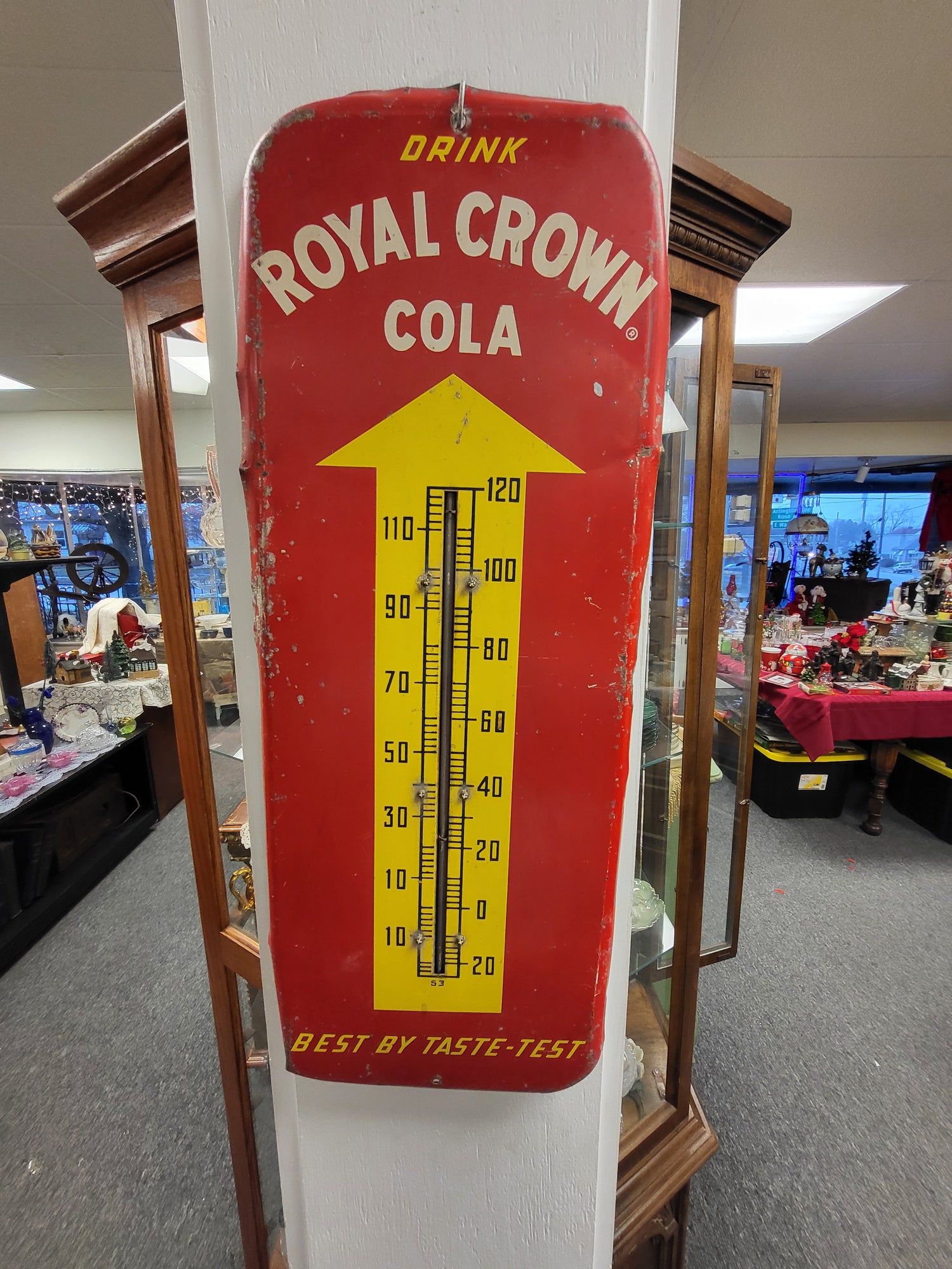 Vintage Royal Crown Cola thermometer on a white surface with a blurred background.