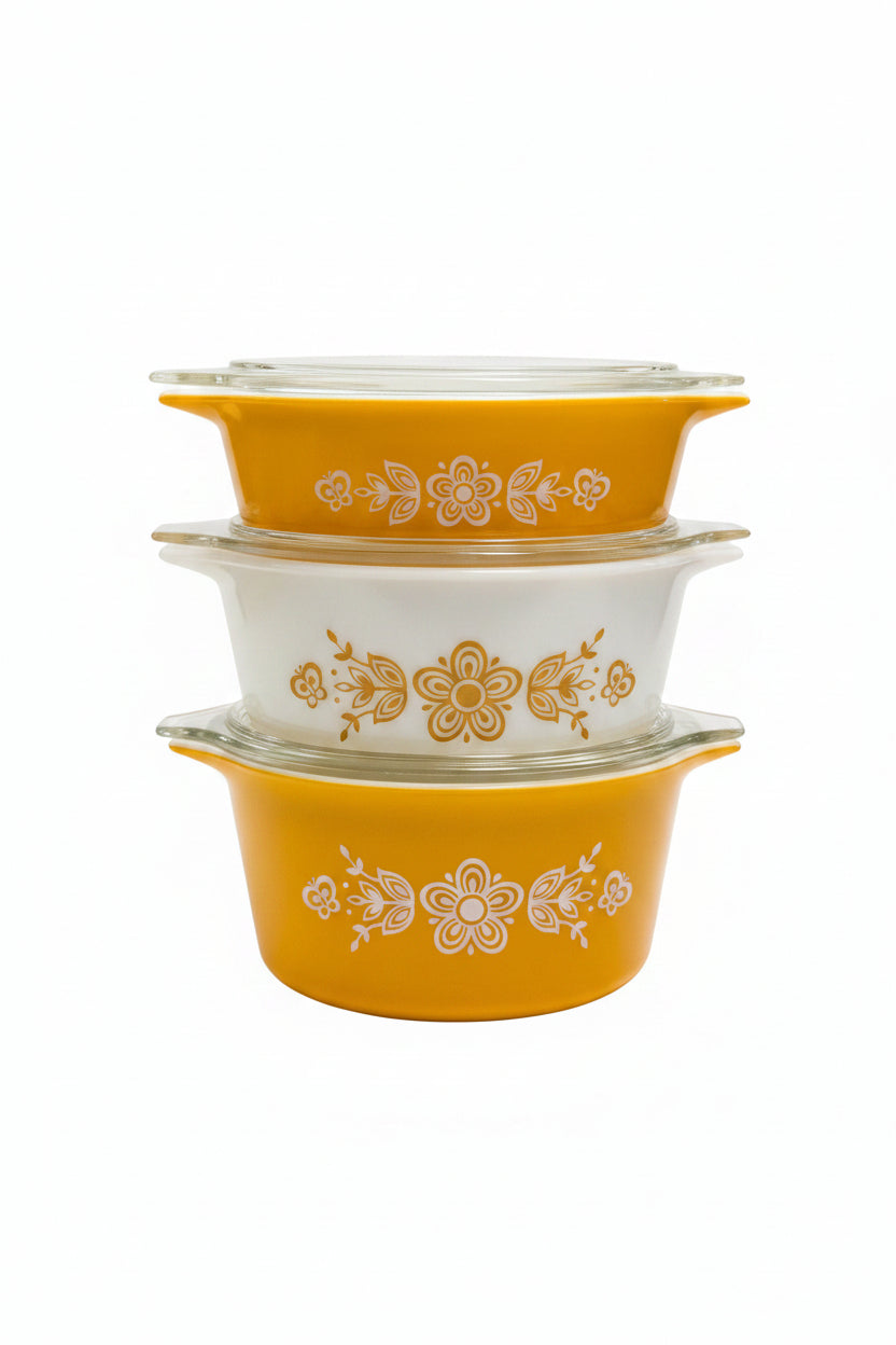Two yellow and white floral-patterned ceramic pots on a wooden surface with a blurred background.