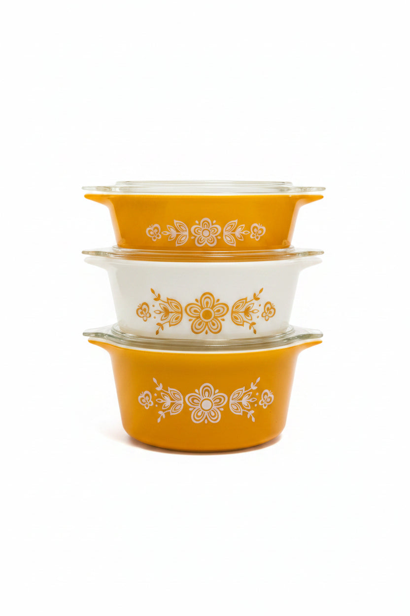 Set of three yellow and white patterned containers on a wooden surface with a blurred background.