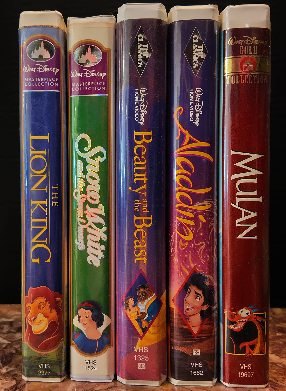 Collection of Disney VHS tapes including 'The Lion King', 'Snow White', 'Beauty and the Beast', 'Aladdin', and 'Mulan'.