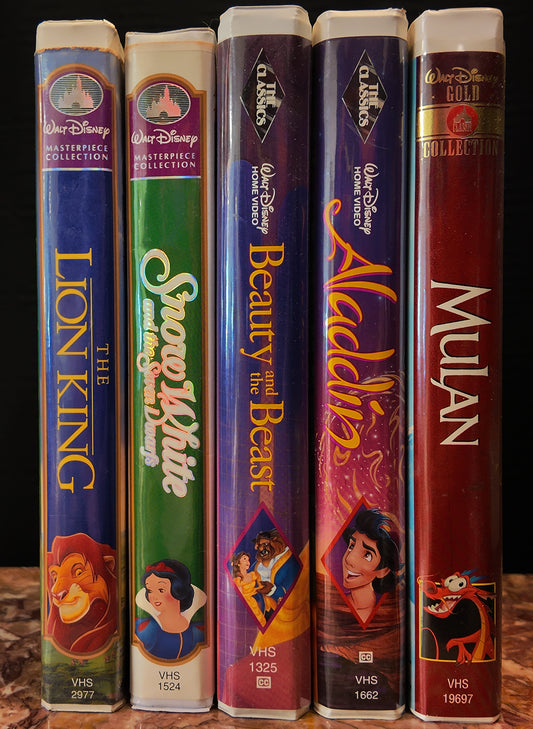 Collection of Disney VHS tapes including 'The Lion King', 'Snow White', 'Beauty and the Beast', 'Aladdin', and 'Mulan'.