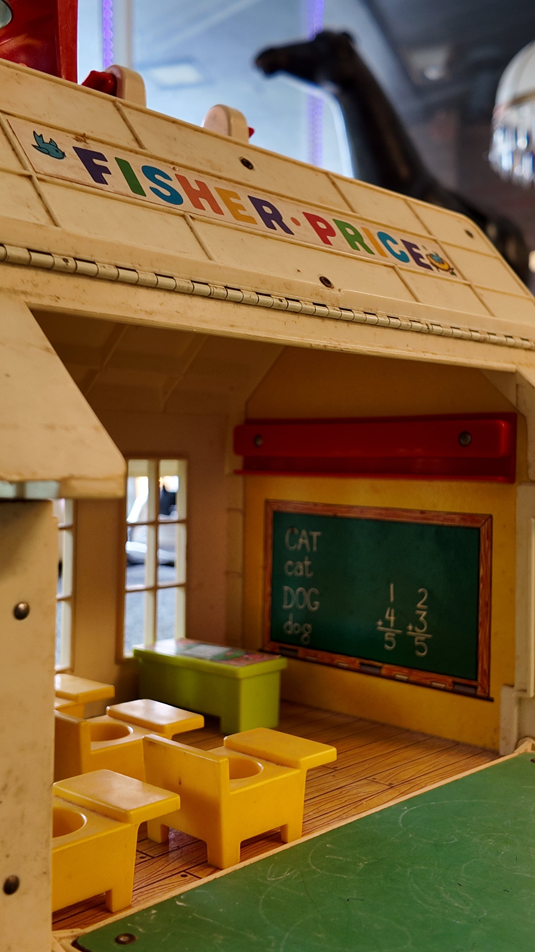 Vintage Fisher-Price toy with wooden structure, yellow chairs, and green chalkboard.