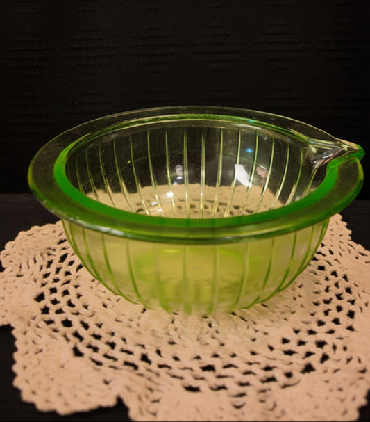 Green glass bowl on a doily with a dark background